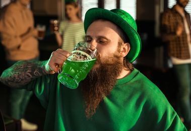 Photo of Man drinking green beer in pub. St. Patrick's Day celebration