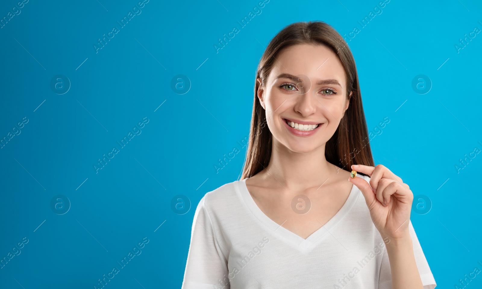 Photo of Young woman with vitamin pill on blue background