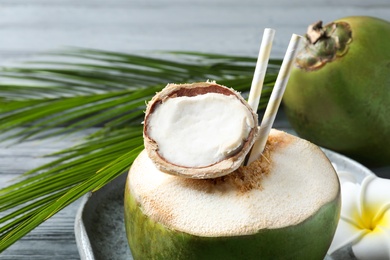 Photo of Fresh green coconut with drinking straws on table, closeup