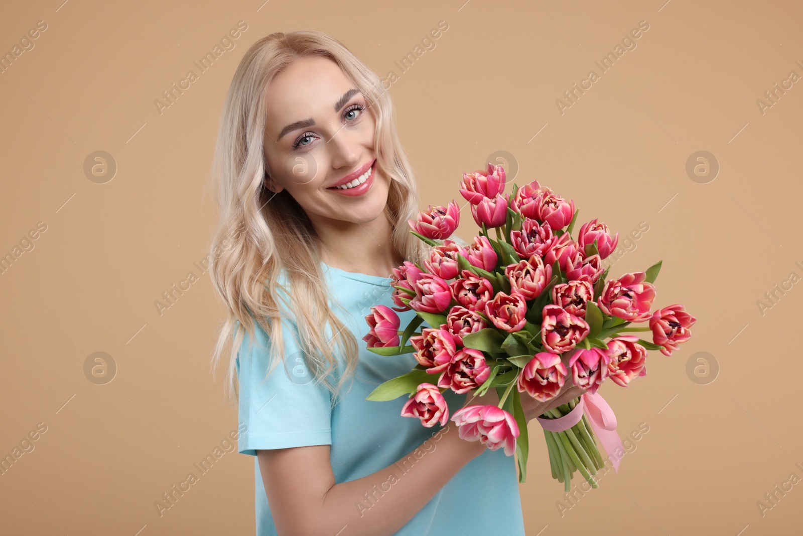 Photo of Happy young woman with beautiful bouquet on beige background