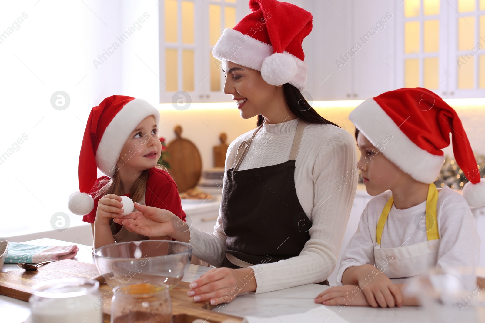 Photo of Mother with her cute little children making Christmas cookies in kitchen