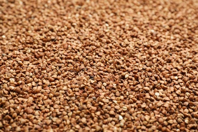 Photo of Uncooked organic buckwheat grains as background, closeup