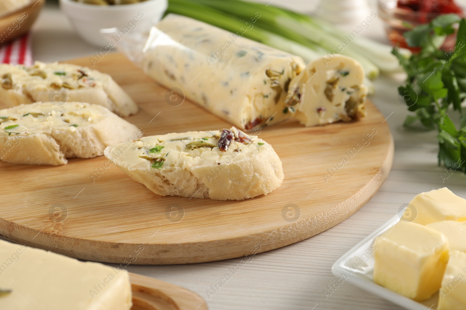 Photo of Tasty butter with olives, green onion, chili pepper and bread on wooden table