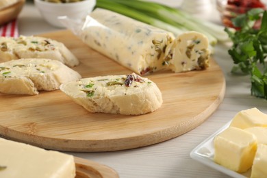 Photo of Tasty butter with olives, green onion, chili pepper and bread on wooden table