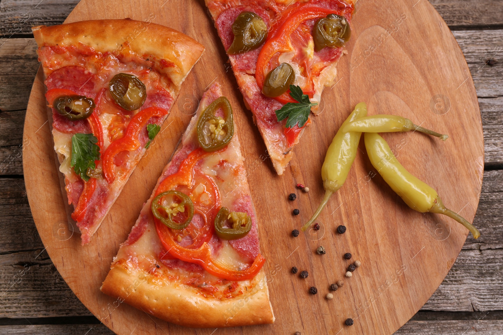 Photo of Pieces of delicious pizza Diablo, pickled peppers and spices on wooden table, top view