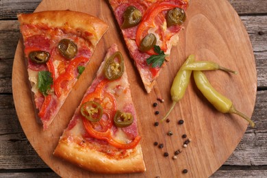 Photo of Pieces of delicious pizza Diablo, pickled peppers and spices on wooden table, top view