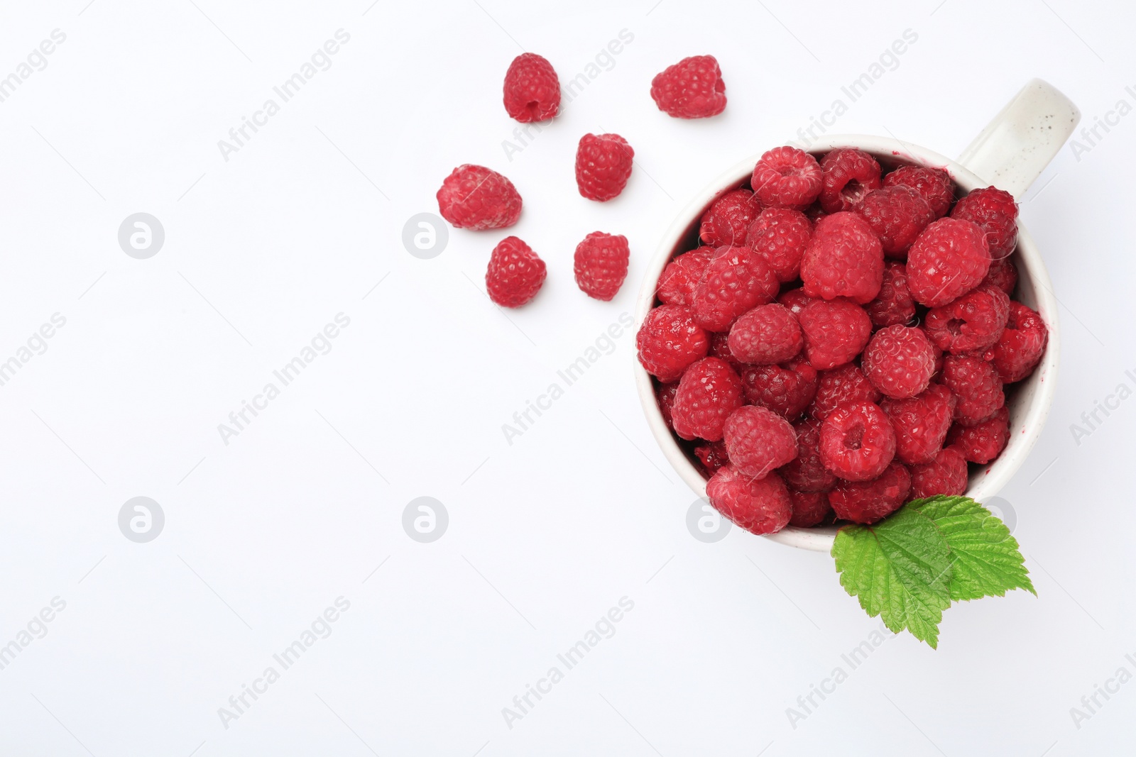 Photo of Mug with ripe raspberries on white background, top view