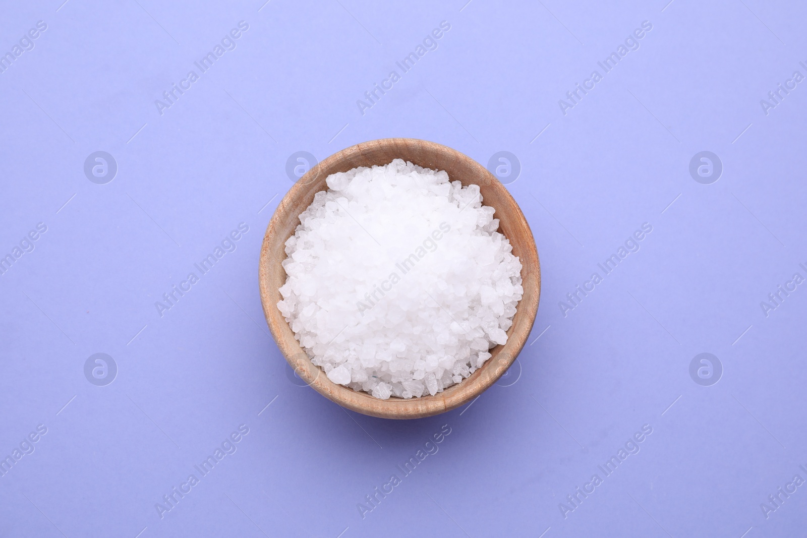 Photo of Bowl of sea salt on violet background, top view