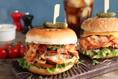 Tasty burgers with bacon served on table