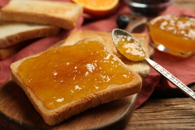 Photo of Delicious toasts with jam served on wooden table, closeup