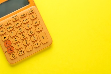 Orange calculator on yellow background, top view. Space for text