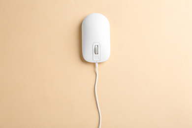Modern wired optical mouse on beige background, top view