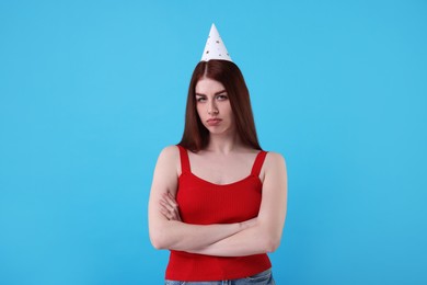 Photo of Sad woman in party hat on light blue background