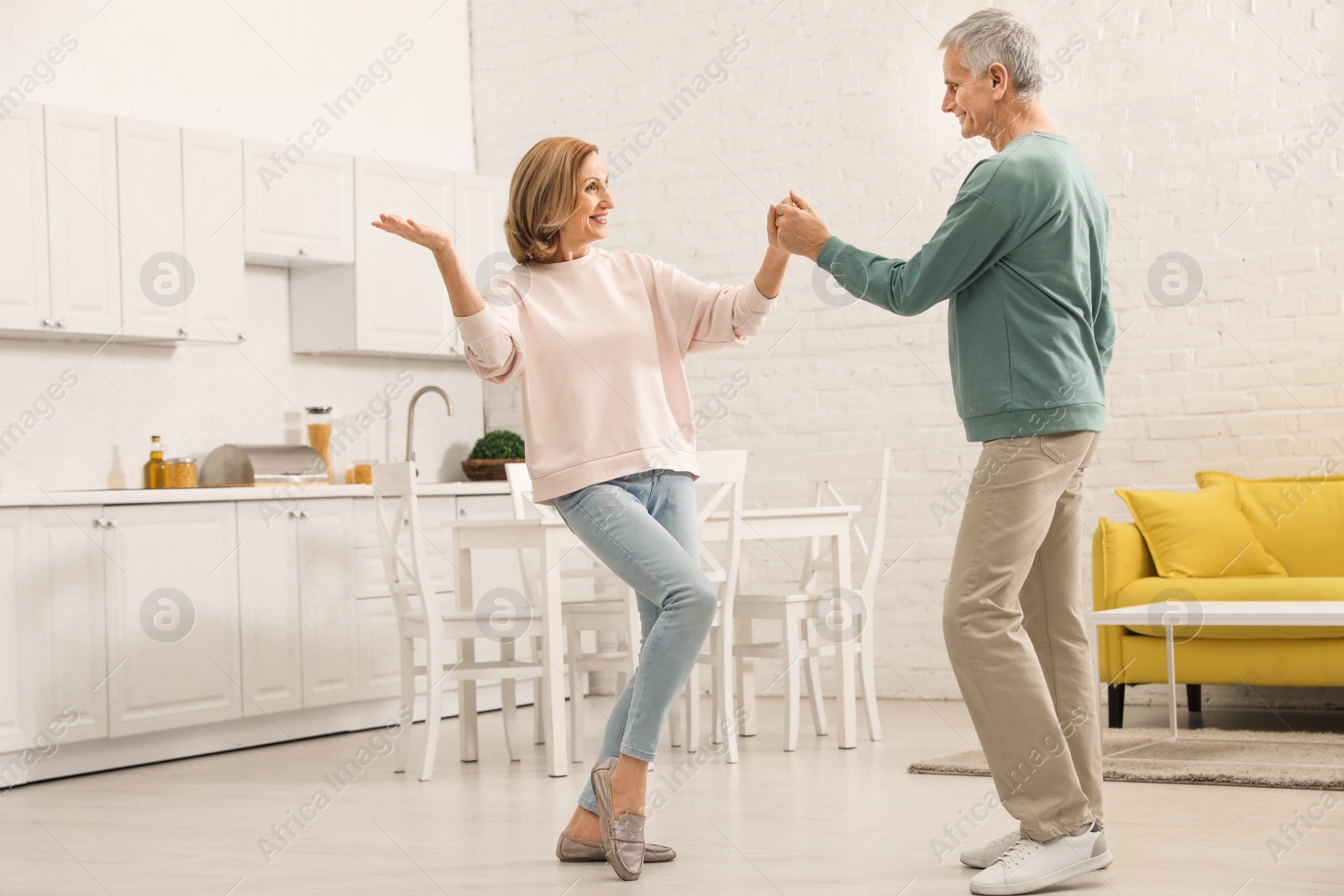 Photo of Happy senior couple dancing together in kitchen