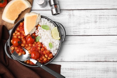 Delicious chickpea curry with rice served on white wooden table, flat lay. Space for text