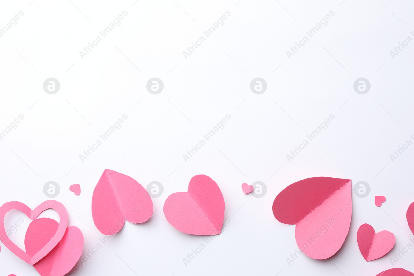 Photo of Pink paper hearts on white background, flat lay. Space for text