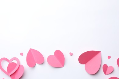 Pink paper hearts on white background, flat lay. Space for text