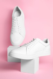 Photo of Pair of stylish white sneakers on pink background