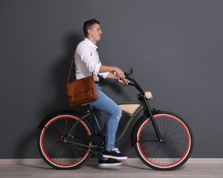 Photo of Portrait of handsome young man with bicycle near color wall