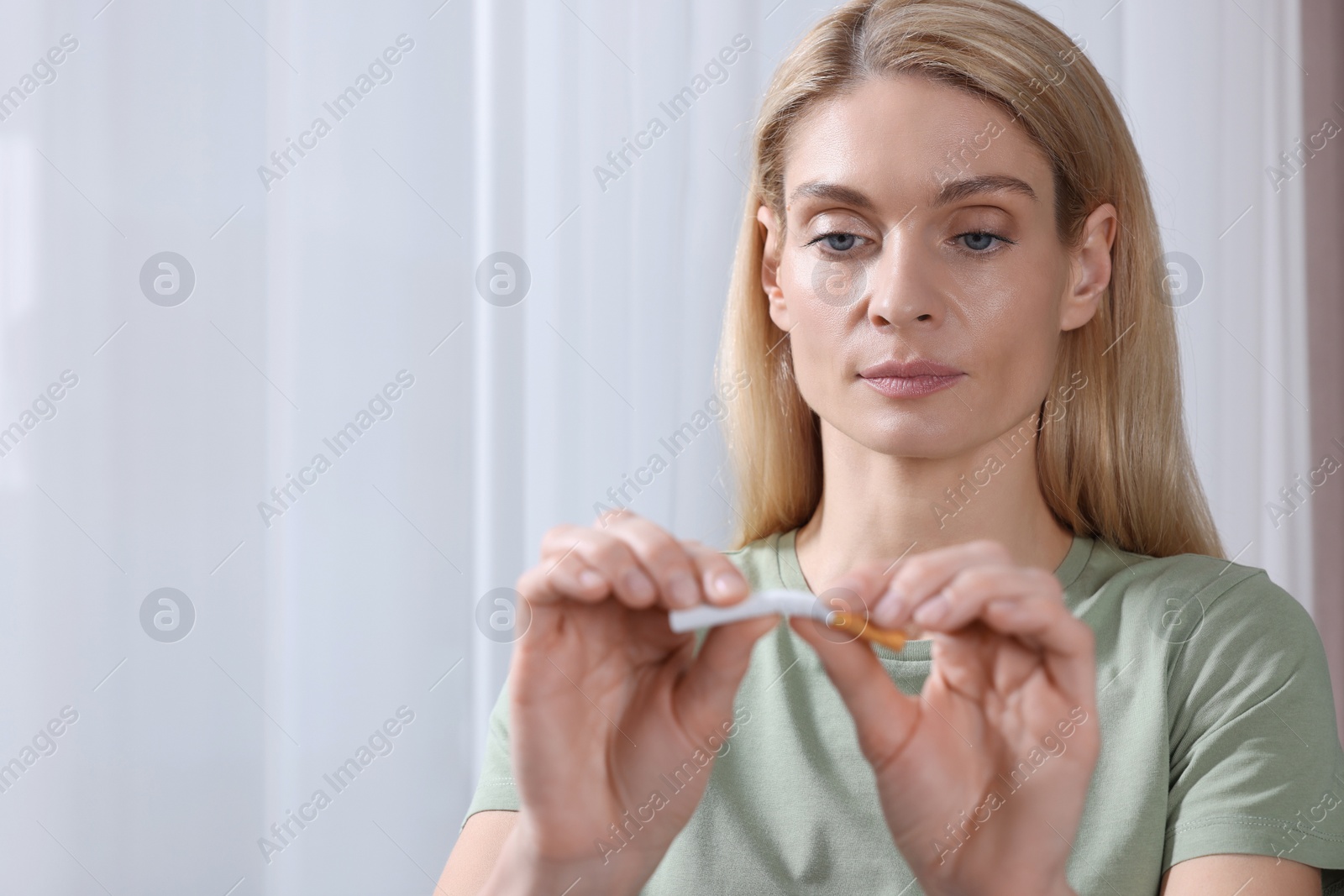 Photo of Quitting smoking concept. Woman breaking cigarette on light background. Space for text