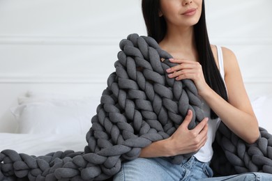 Photo of Woman with chunky knit blanket on bed at home, closeup