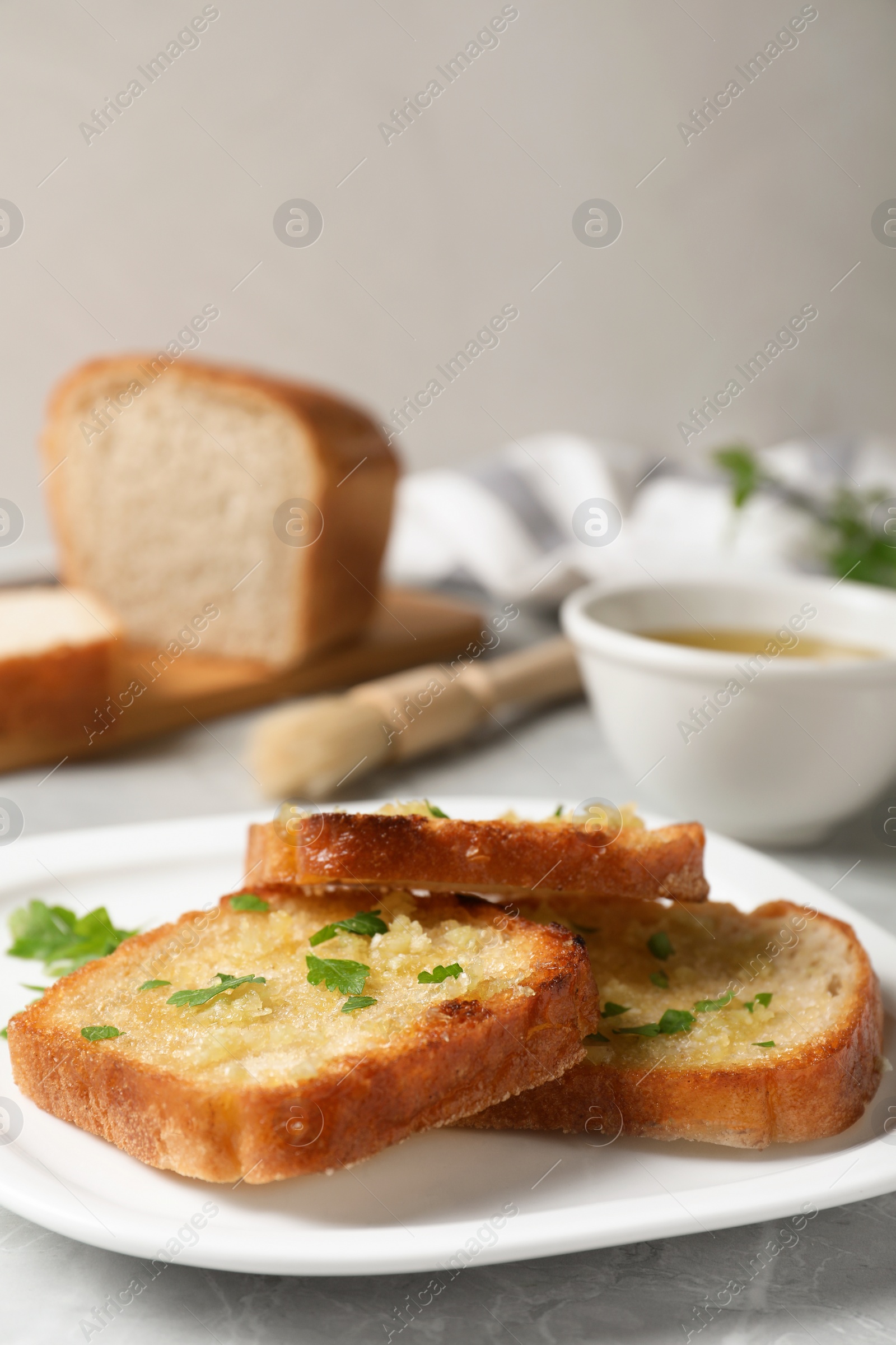 Photo of Slices of toasted bread with garlic and herb on light grey marble table