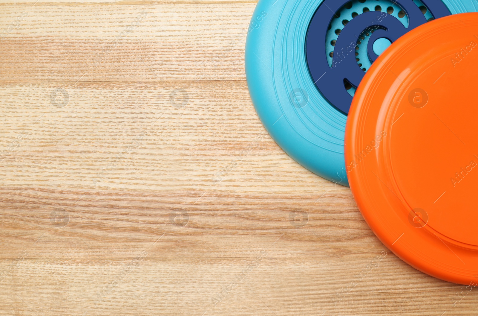 Photo of Plastic frisbee disks on wooden background, flat lay. Space for text