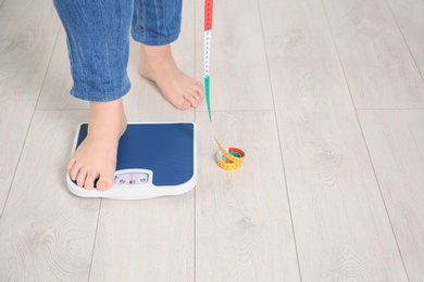 Overweight woman using scales indoors