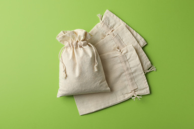 Photo of Cotton eco bags on light green background, flat lay