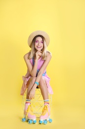 Young woman with retro roller skates on color background