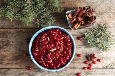 Flat lay composition with cranberry sauce in bowl on wooden background