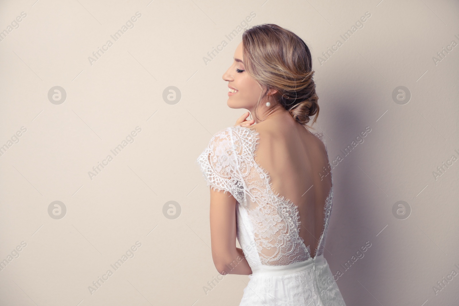 Photo of Young bride with elegant wedding hairstyle on beige background. Space for text