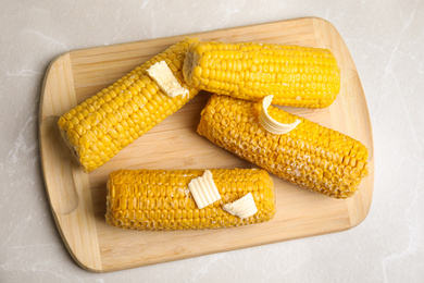 Photo of Delicious boiled corn on light grey marble table, top view