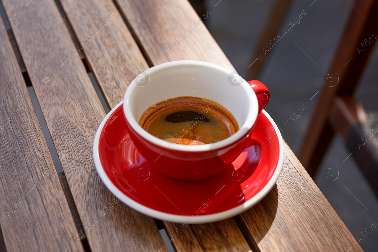 Photo of Cup of aromatic hot coffee on wooden table outdoors