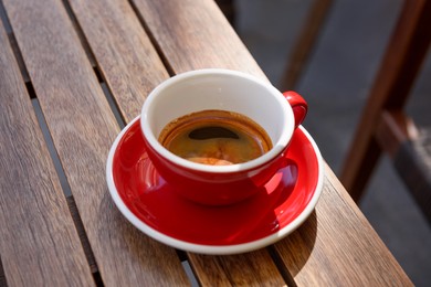 Cup of aromatic hot coffee on wooden table outdoors