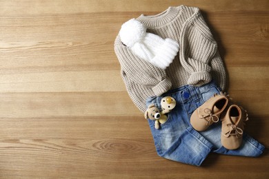 Children's shoes, clothes, toy and pacifier on wooden table, flat lay. Space for text