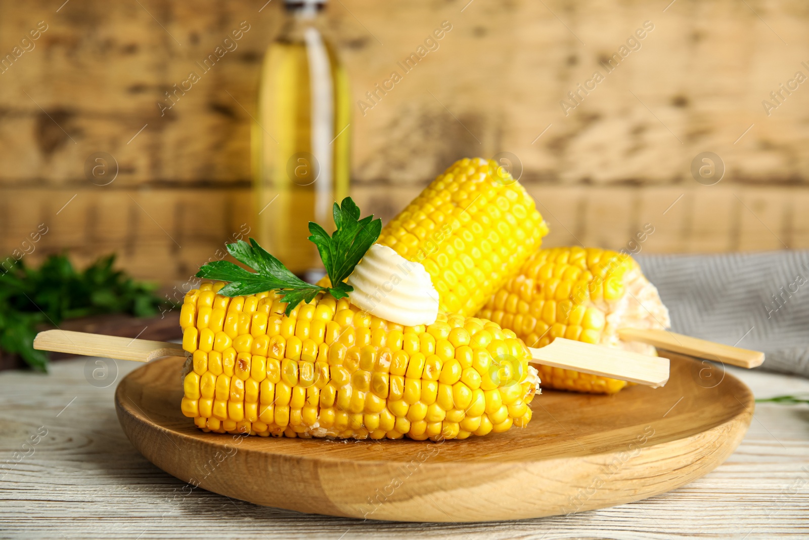 Photo of Fresh corn cobs with butter on white wooden table, closeup