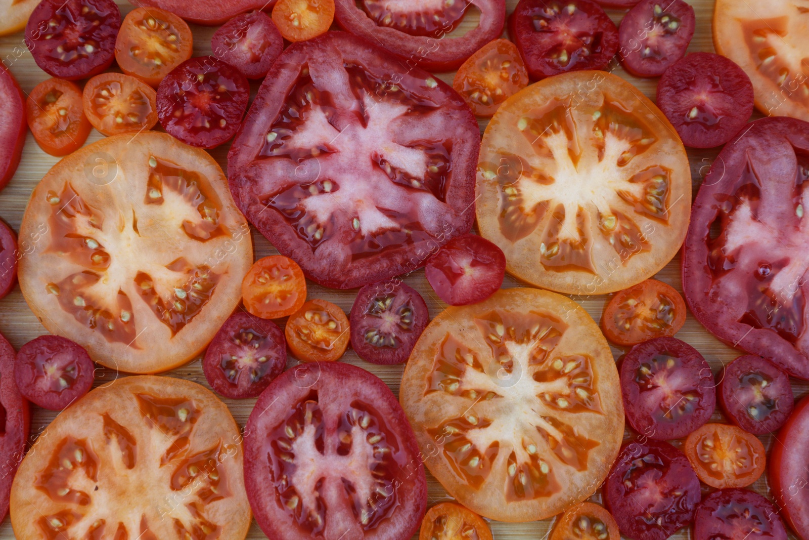 Photo of Cut tomatoes of different sorts on wooden table, flat lay