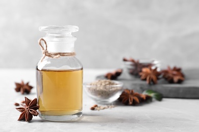 Photo of Anise essential oil and spice on light table, space for text