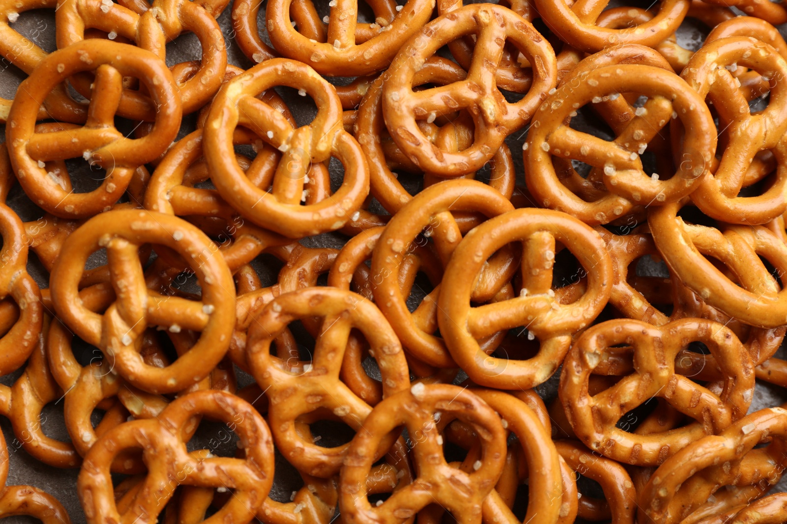 Photo of Many delicious pretzel crackers as background, top view
