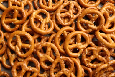 Many delicious pretzel crackers as background, top view