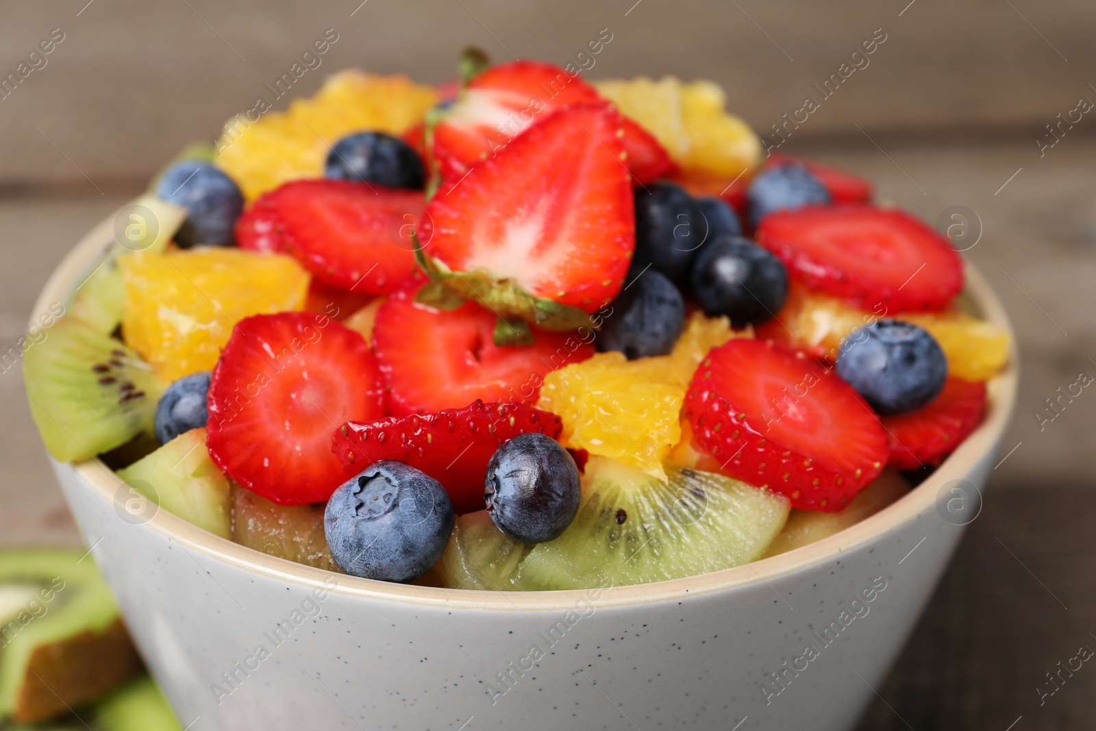 Photo of Delicious fresh fruit salad in bowl on table, closeup