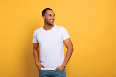 Photo of Portrait of happy African American man on orange background. Space for text