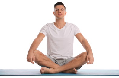 Photo of Handsome man meditating on yoga mat against white background