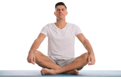 Handsome man meditating on yoga mat against white background