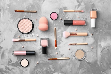 Photo of Flat lay composition with cosmetic products and makeup brushes on grey background