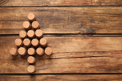 Photo of Christmas tree made of wine corks on wooden table, top view. Space for text