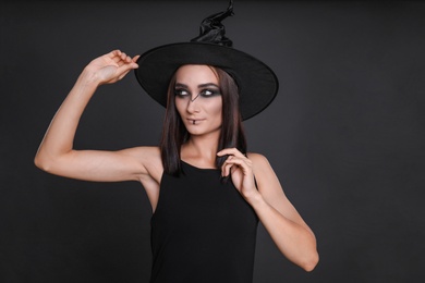 Photo of Mysterious witch wearing hat on black background