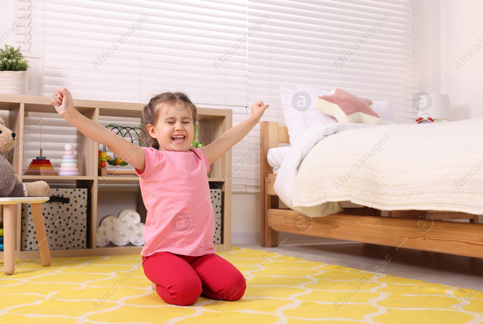 Photo of Cute little girl stretching in cosy bedroom