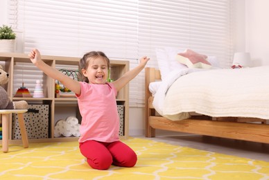 Photo of Cute little girl stretching in cosy bedroom